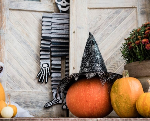 Halloween decorated front door with various size and shape pumpkins and skeletons