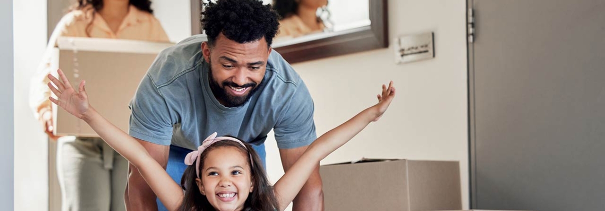 A young father having fun with his daughter while pushing her in a moving box
