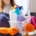 woman in rubber gloves with basket of cleaning supplies ready to clean up her apartment