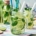 Two glasses and a bottle of homemade lemon, lime, and mint lemonade sit on the wooden dining table
