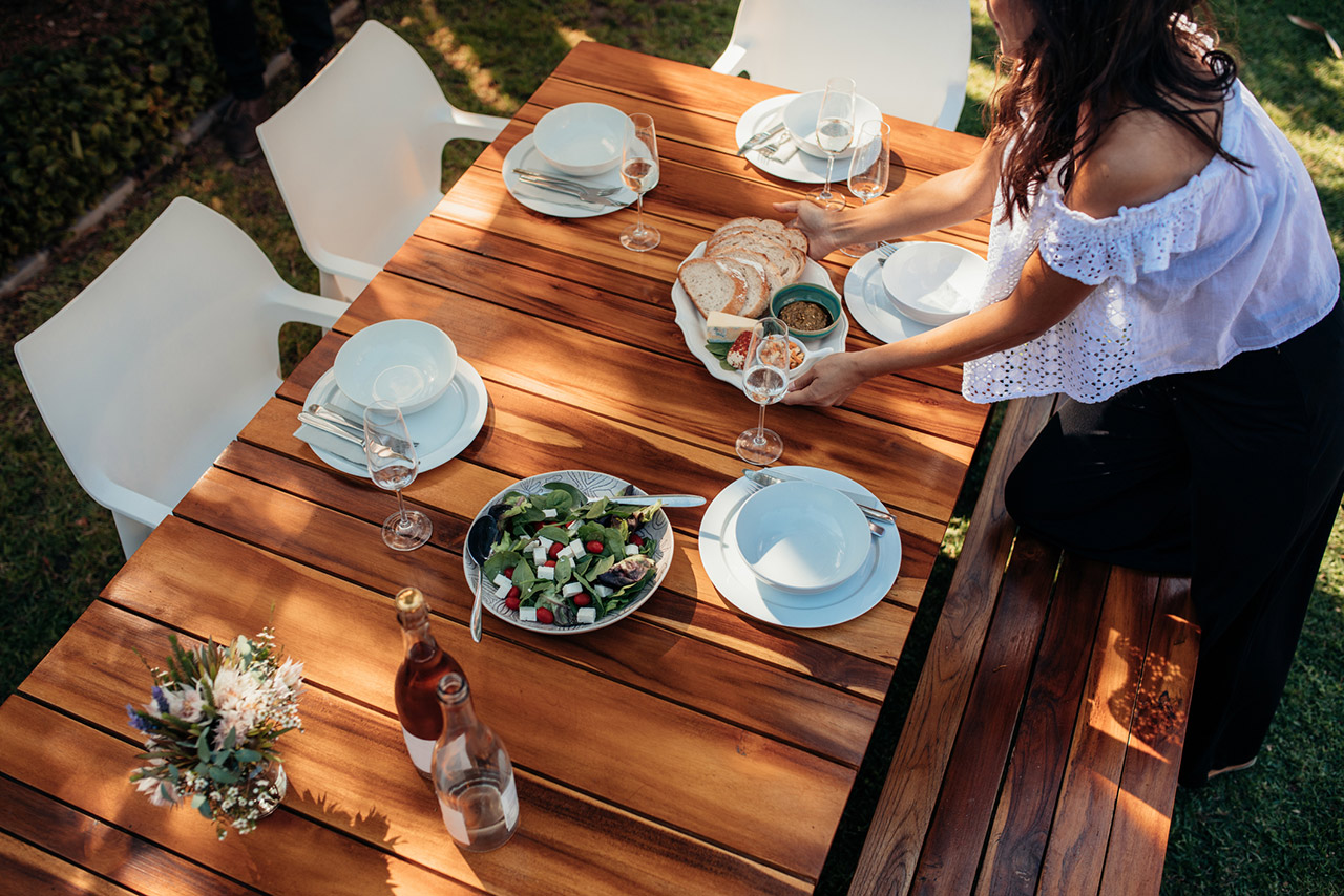 Top view of woman setting food on wooden table for housewarming party.