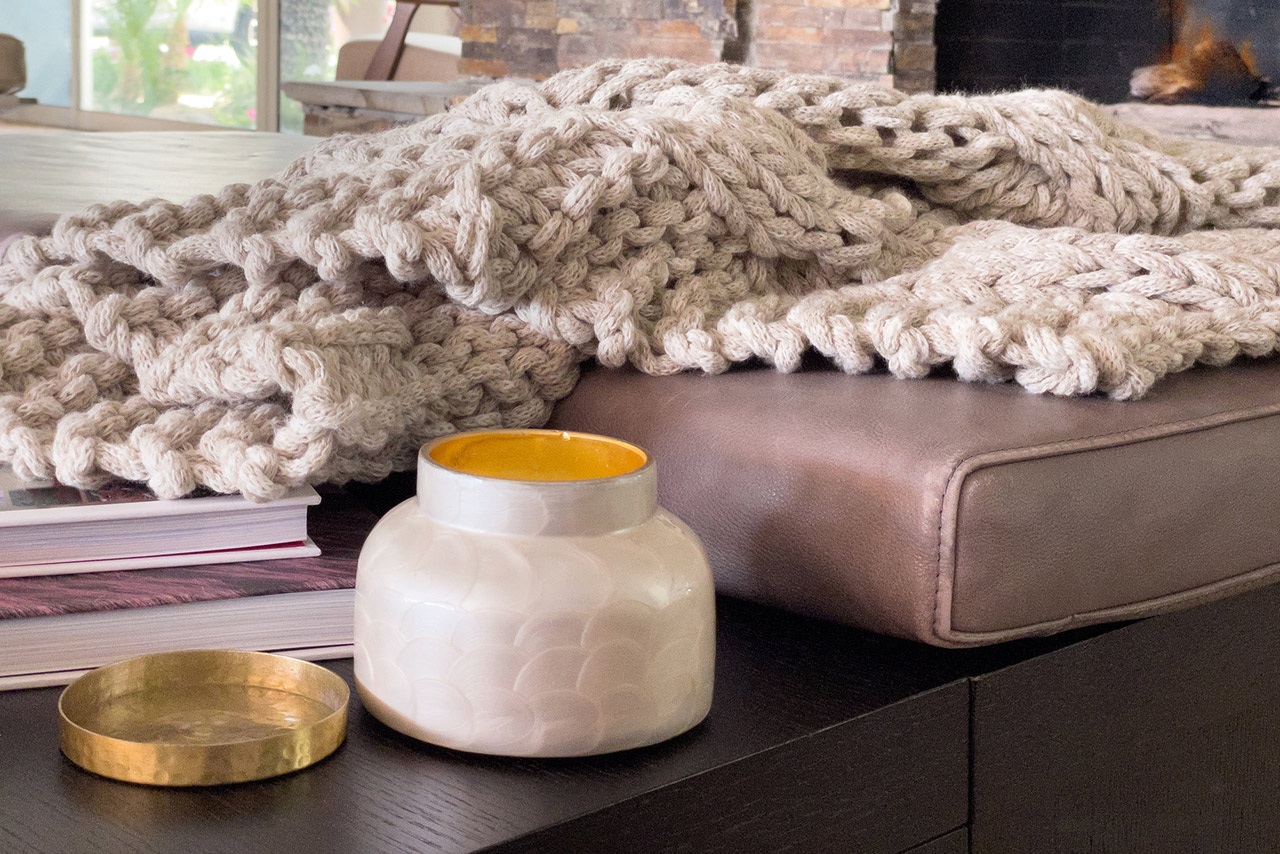 Warm comfy living room setting with candle and chunky afgan with thick gray yarn stock photo